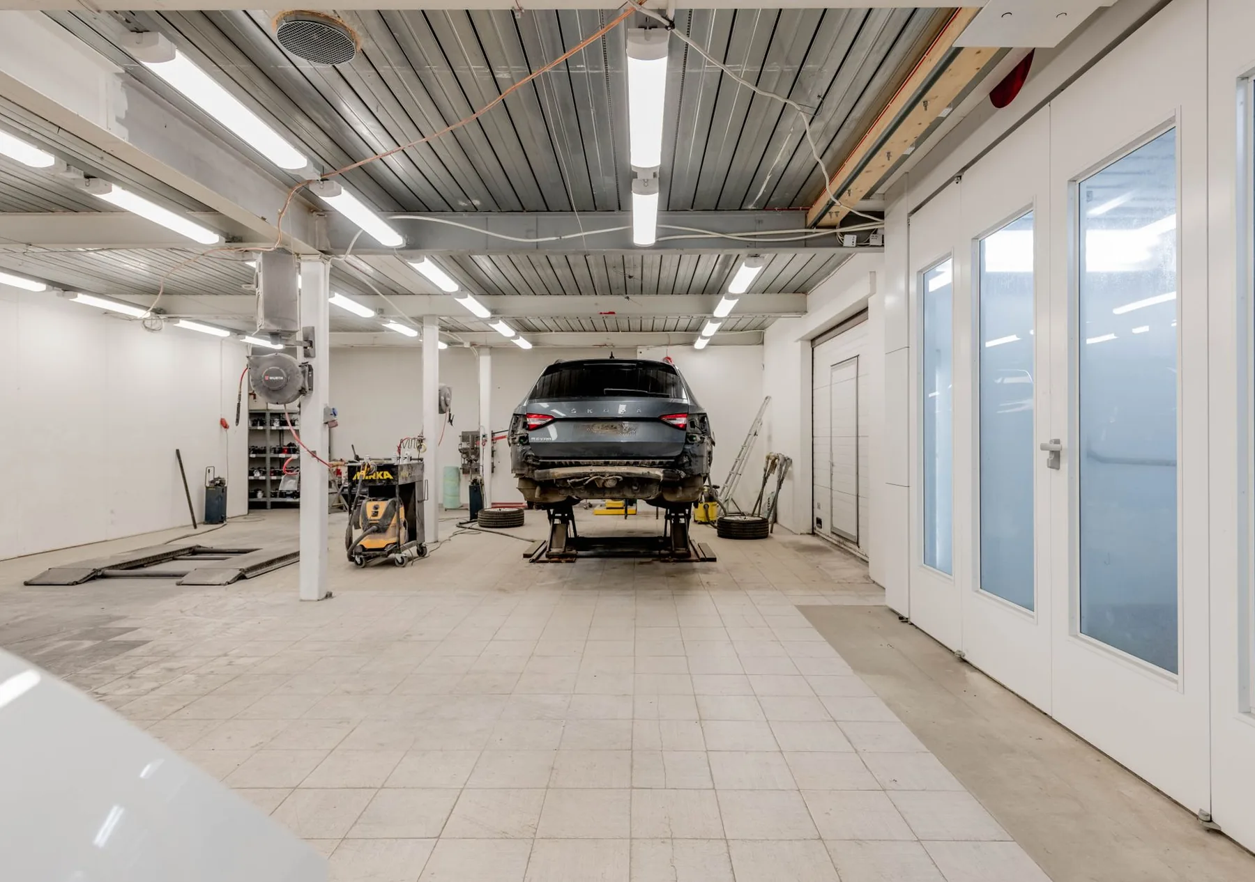 A car raised on a hydraulic lift in a bright workshop
