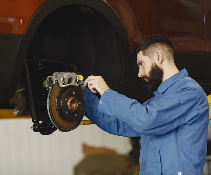 A mechanic working on a brake disc and caliper