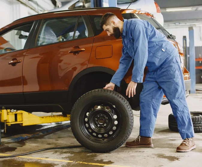 A mechanic fitting a wheel to a vehicle on a lift