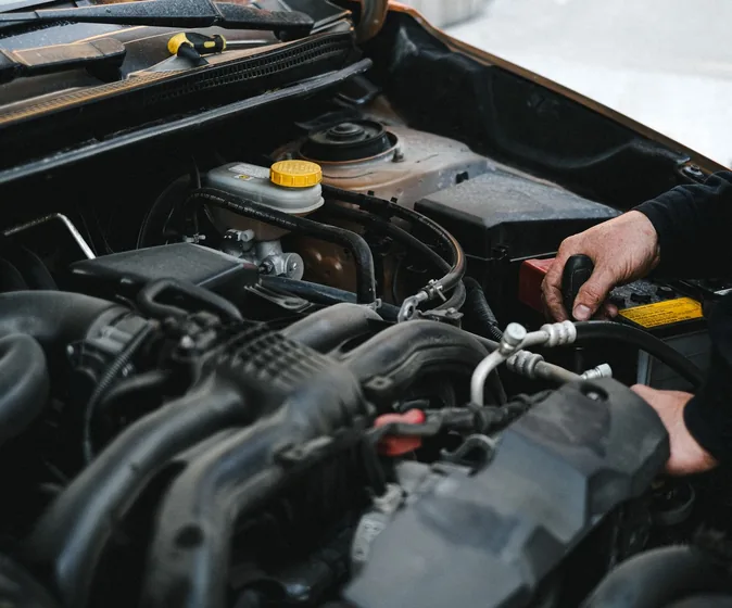 A mechanic's hands working in an open engine bay