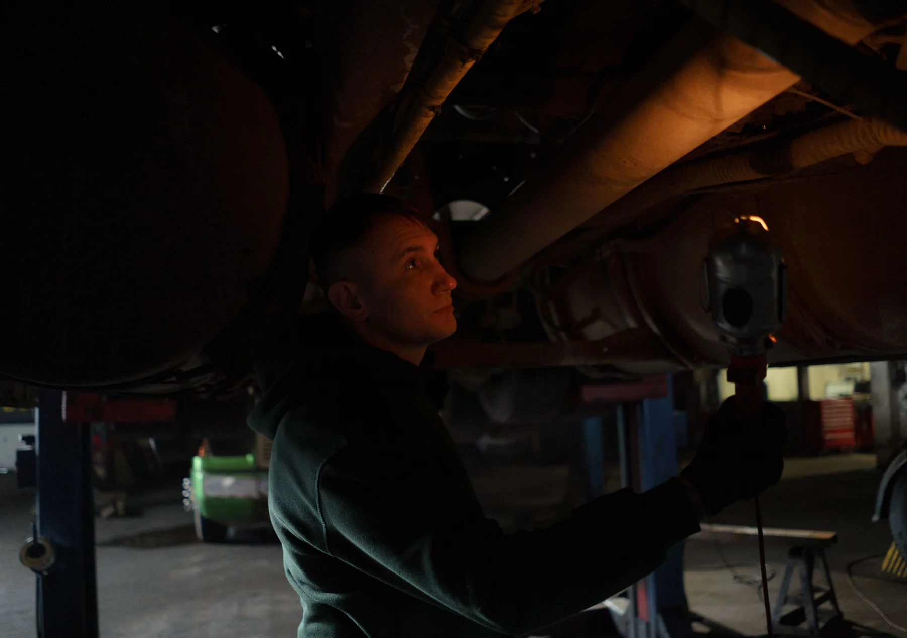 A mechanic inspecting the underside of a vehicle on a lift
