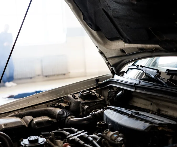 Car engine under an open hood in a well-lit garage