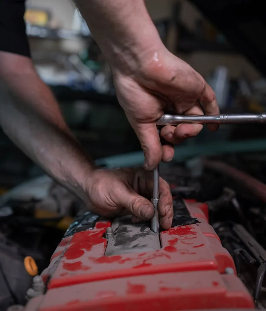 Mechanic using a socket wrench on a car engine in a garage