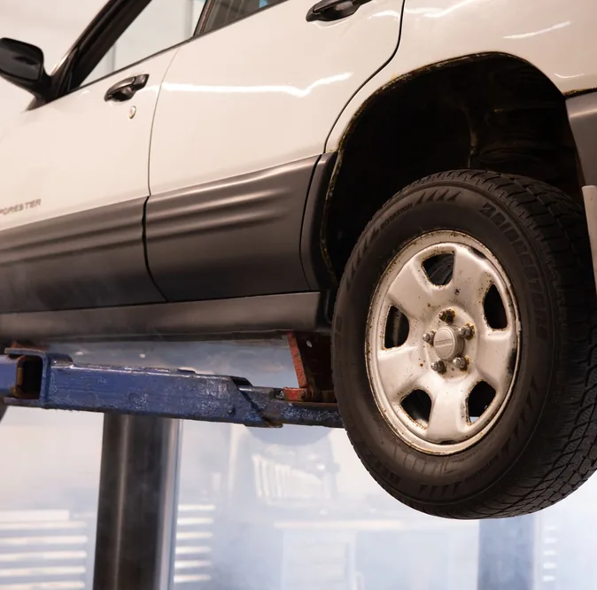 White car suspended on a lift inside an auto repair shop